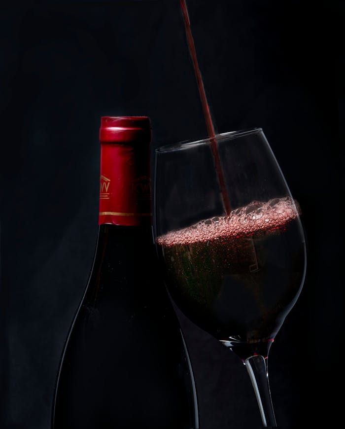 Elegant red wine pouring into a glass with a bottle in background, perfect for wine enthusiasts.
